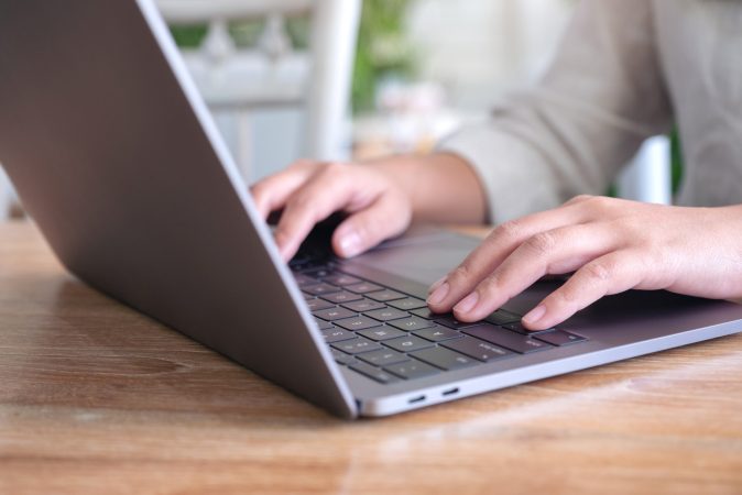 Closeup image of woman's hands using and typing on laptop keyboa